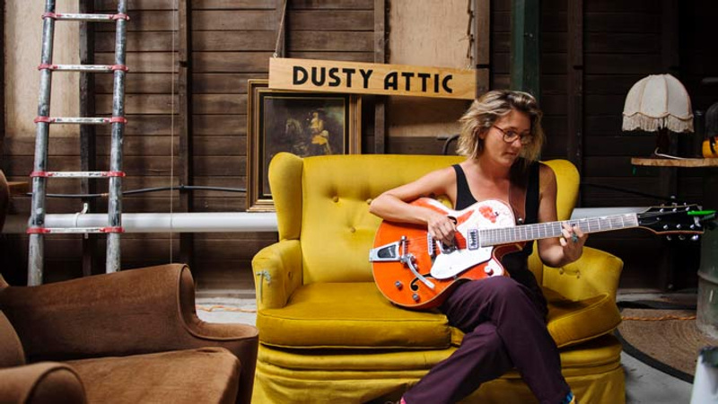 Woman sitting in chair playing a guitar