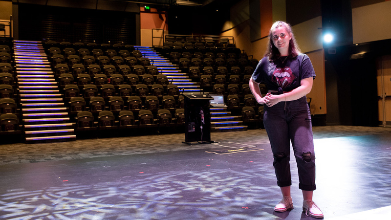Female student standing on-stage with empty seating in the background - Coomera campus