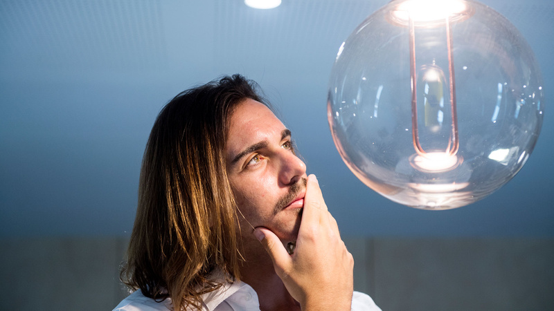 Young man looking at large lightbulb