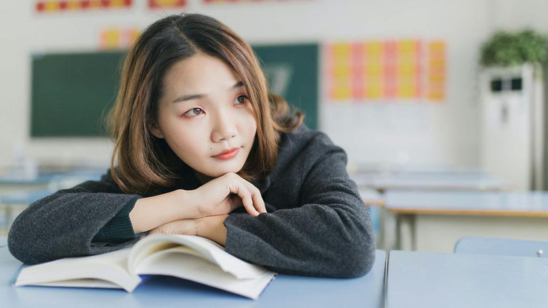 Female student leaning on an open book