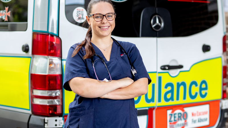 Woman in scrubs standing in front of ambulance