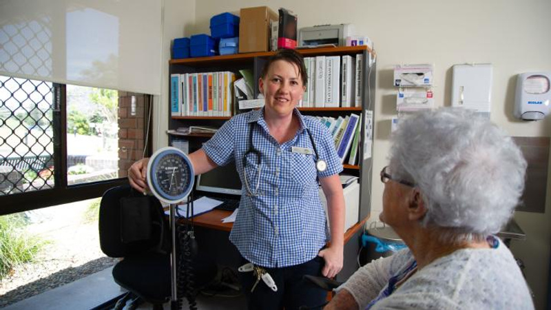 Nurse with stethoscope talks with elderly patient