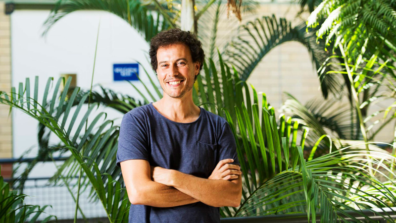 Man standing smiling with tropical plants in background