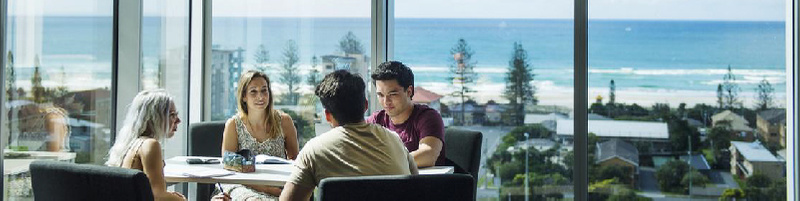 Group of students sitting at desk with Coolangatta beach in background