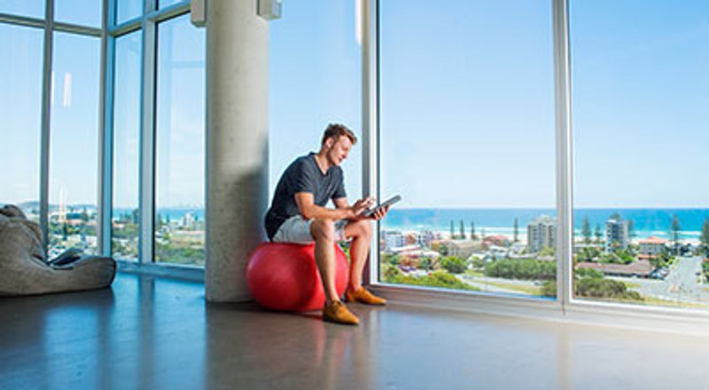 Man studying at Gold Coast campus with ocean in background