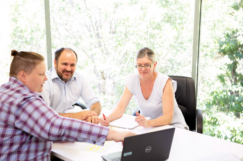 Three people at a meeting looking at a computer screen