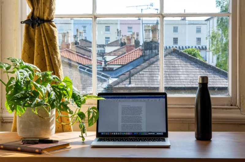 Laptop on desk next to window with views of the neighbourhood