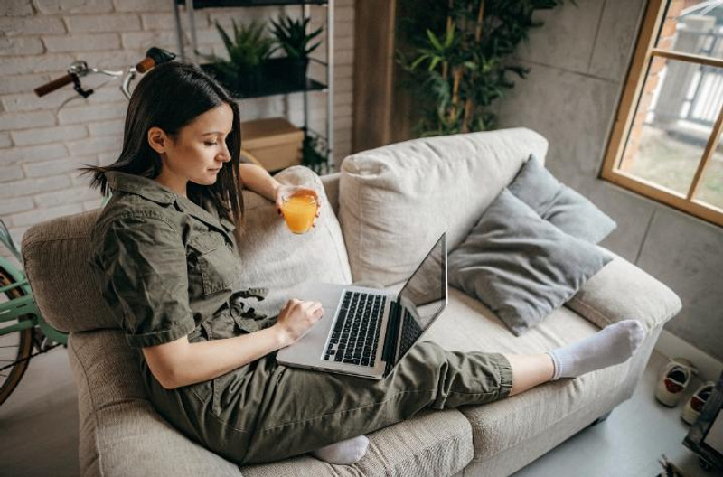 A woman sitting on a lounge with a laptop and coffee