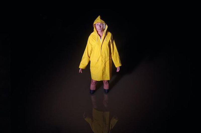 Woman in a yellow raincoast and wellington boots standing in kneehigh water
