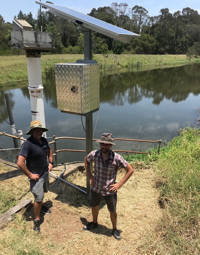 Two men at rivers edge with water monitoring equipment