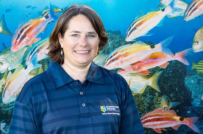 A woman wearing a SCU shirt in front of an underwater mural