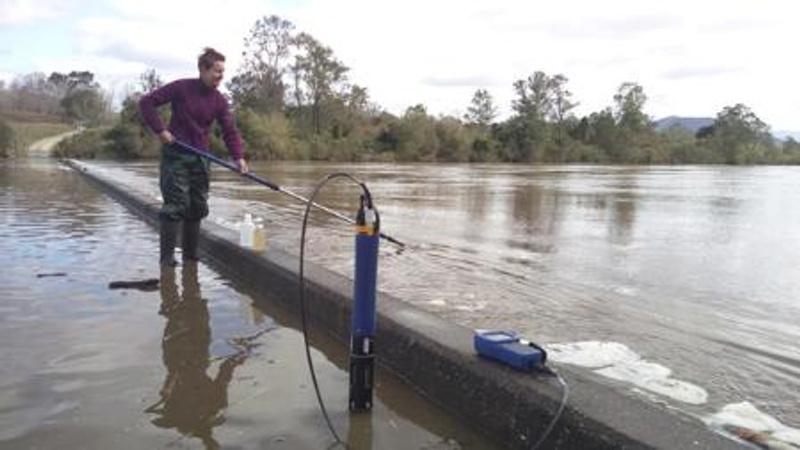 A female scientist samples flood waters with scientific instruments