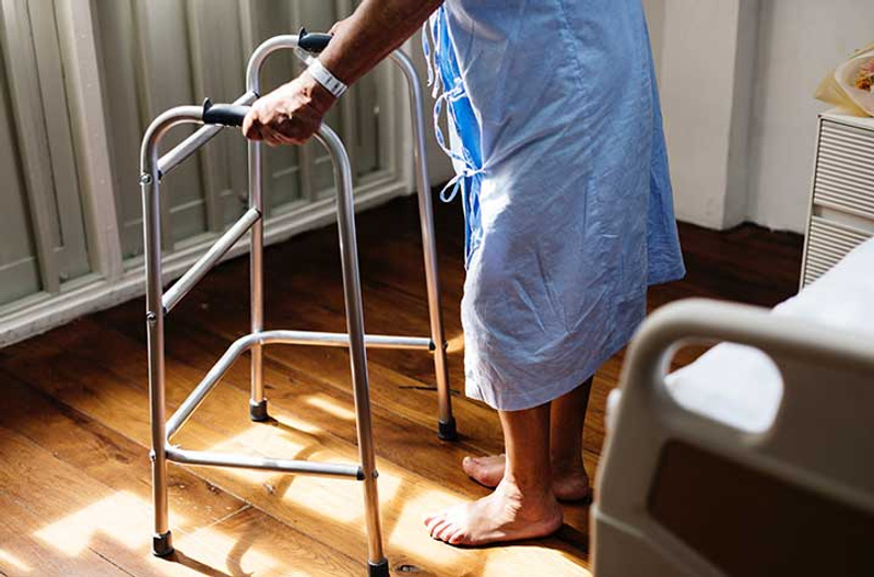 A person standing using adult walker inside room