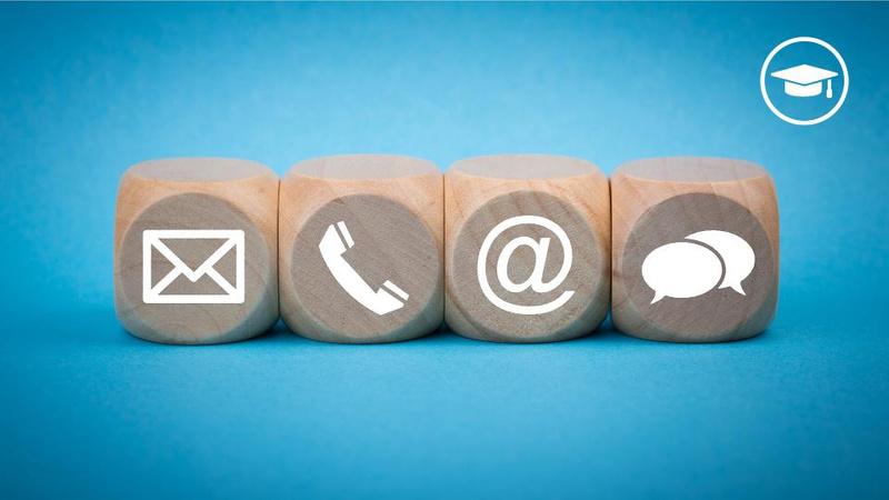 envelope, phone, at, speech bubble and mortar board symbols on wooden dice on blue background