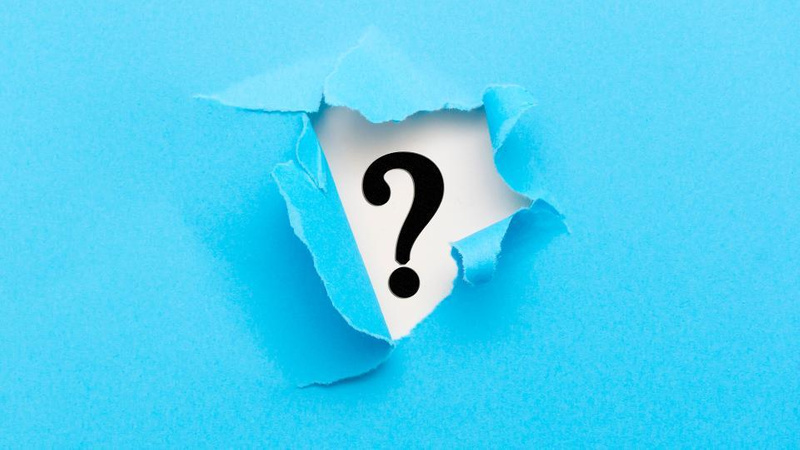 Blue piece of paper with hole ripped in the centre revealing a black questionmark on a white background