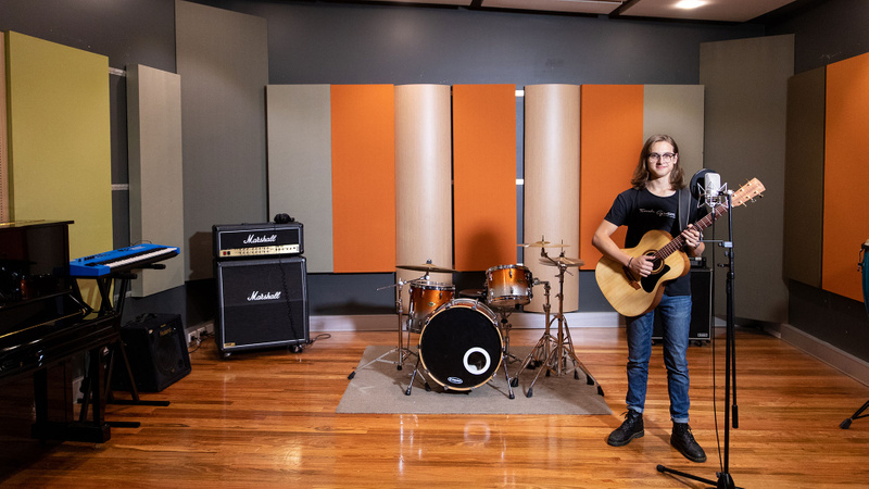 Young man holding guitar in recording space